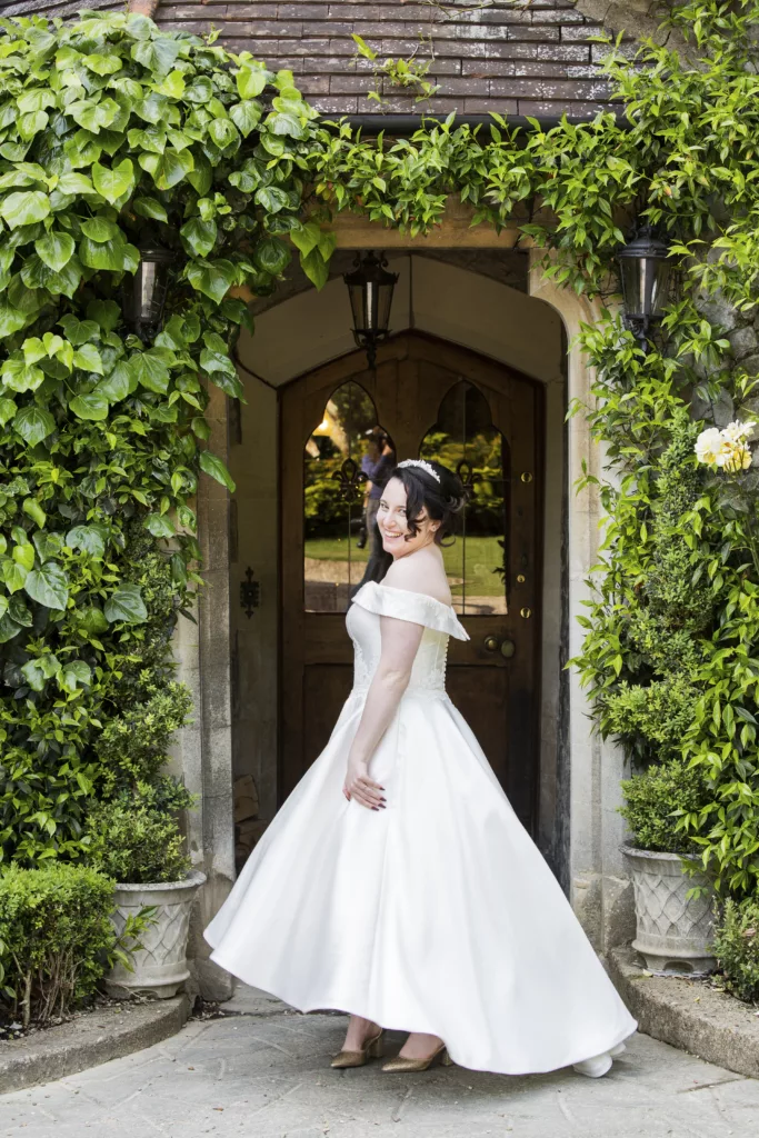 COMFORT IS KEY - BRIDE IN A BEAUTIFUL GOWN UNDER GREEN ARCHWAY - WEDDING PHOTOGRAPHY BY CJ